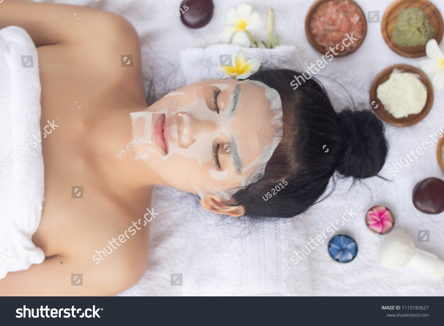 Asian Woman lying with a sheet mask on her face.Wellness body care and spa aromatherapy concept.