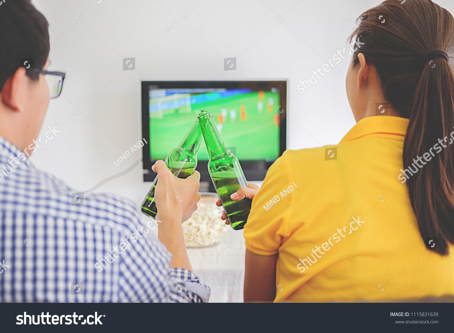 People watch soccer. Asian football supporters watching soccer on television at home with happy emotion.