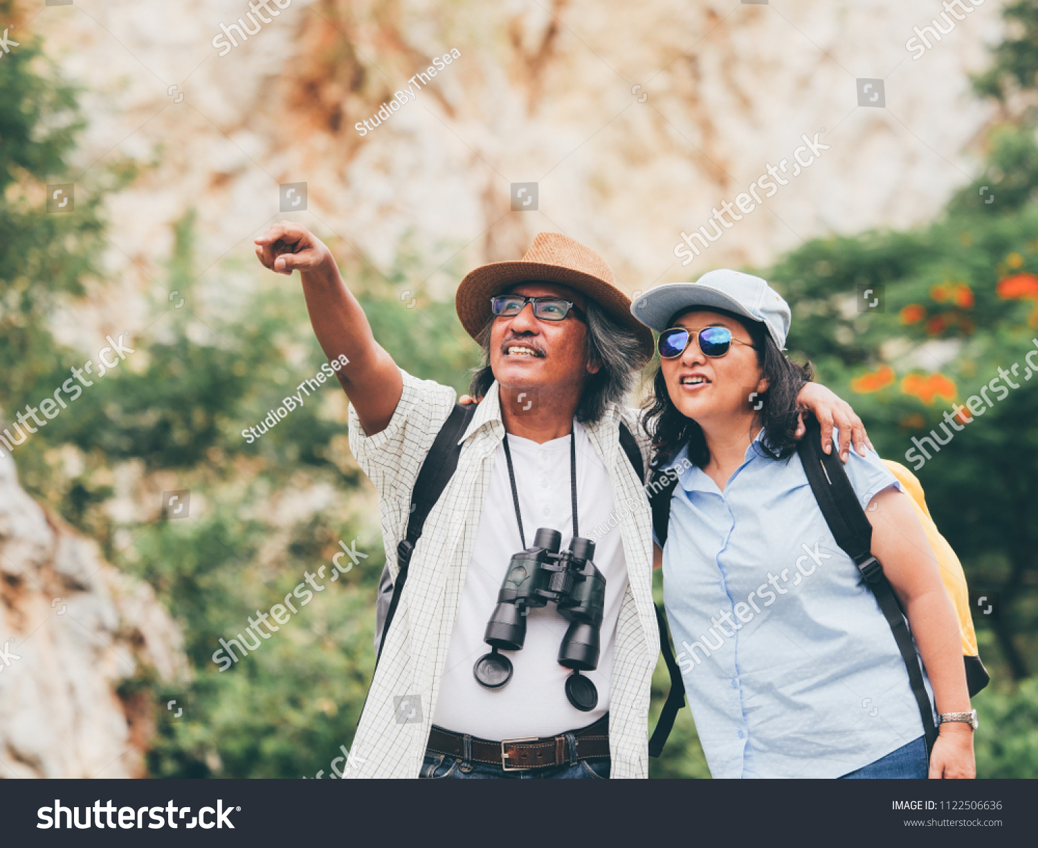 senior couple travel on a summer vacation.they are holding hands and hiking together.