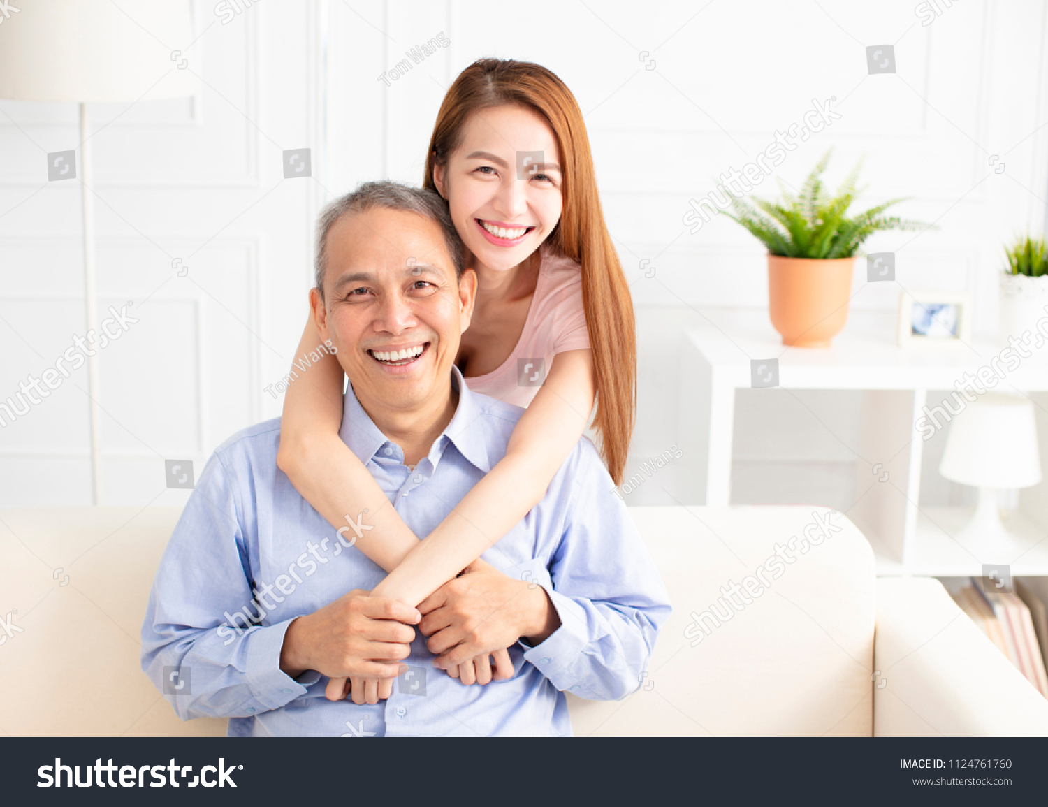 happy asian daughter holding father on sofa