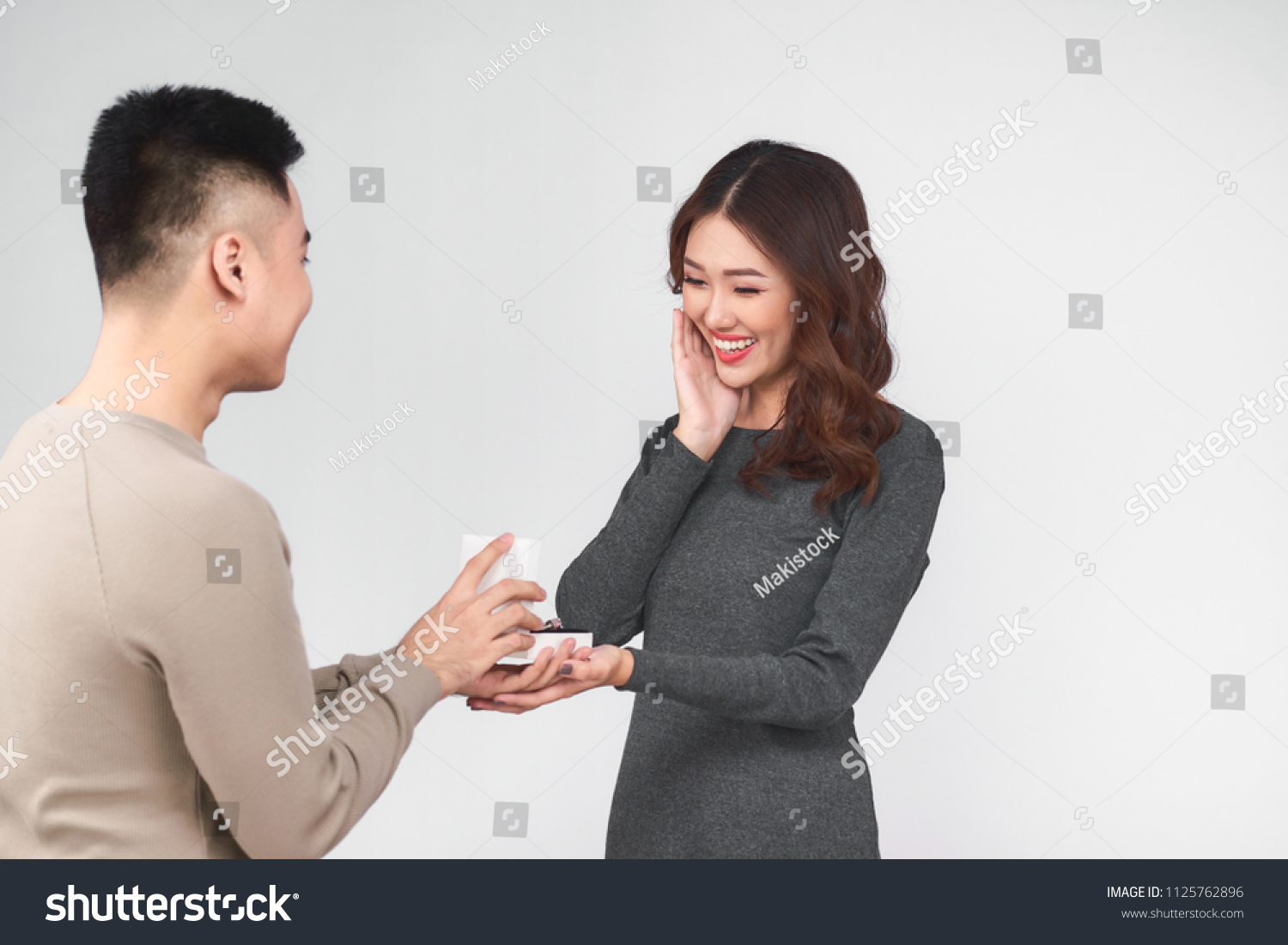 Asian man gives wedding ring and gift box to his woman