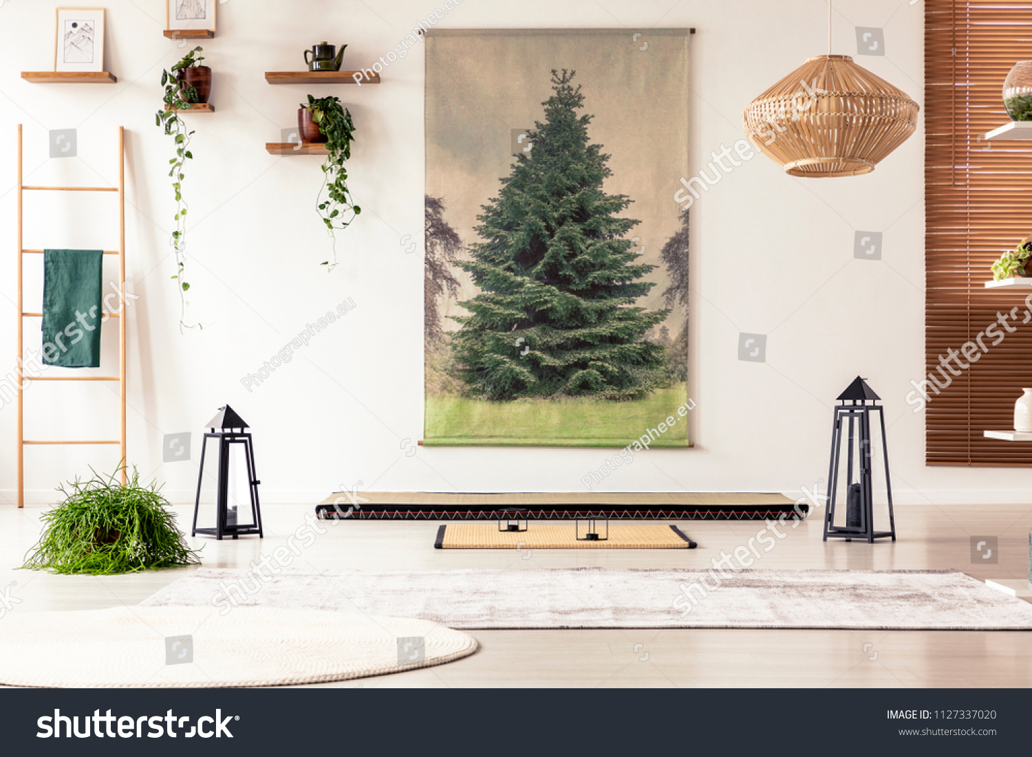 Lanterns and rugs on the floor in bright interior in japanese design with poster and plants. Real photo