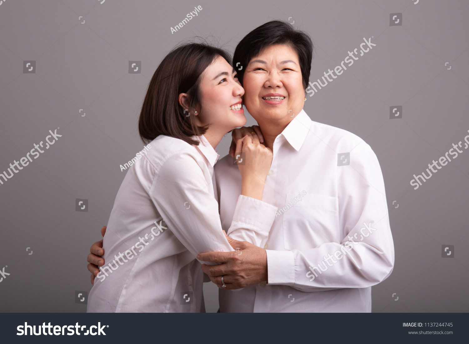 Beautiful senior mom and her adult daughter are hugging  looking at camera and smiling