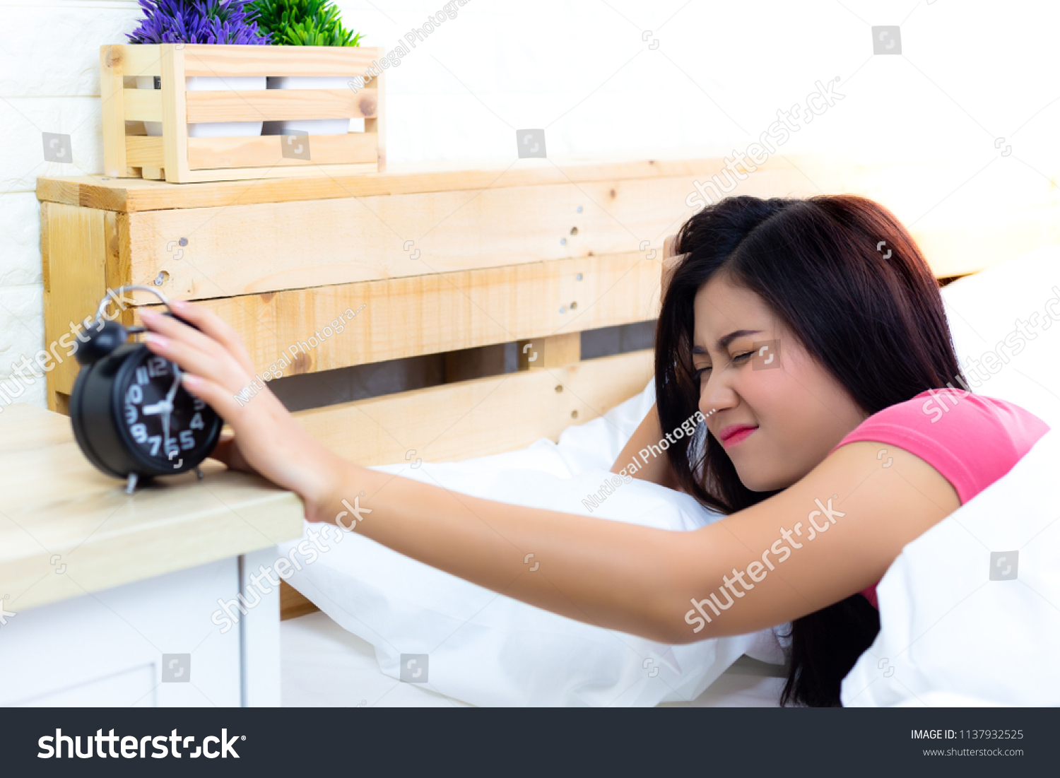 Alarm clock is so loud and wakes beautiful woman up. Attractive beautiful woman gets lazy for going to work on Monday. Pretty girl wakes up so late because lovely woman went to bed so late last night