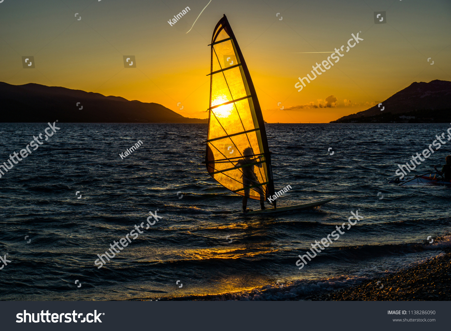 Windsurfing at sunset. Perfect activity for summer.