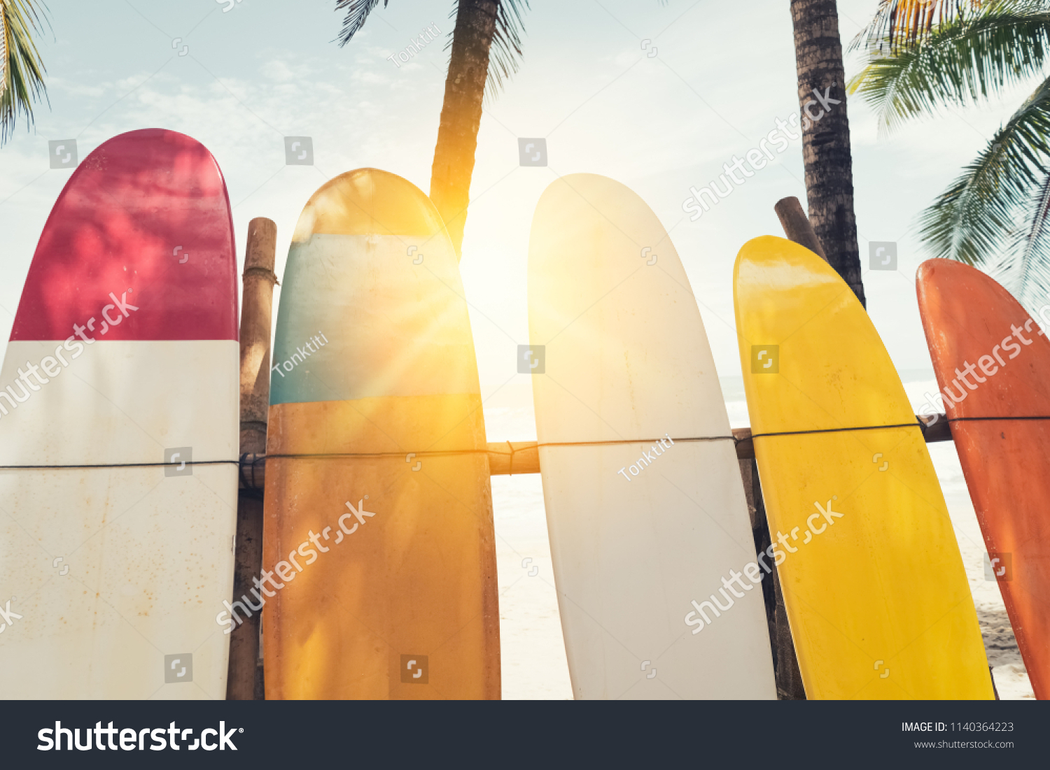 Surfboard and palm tree on beach background. Travel adventure sport and summer vacation concept. Vintage tone filter effect color style.