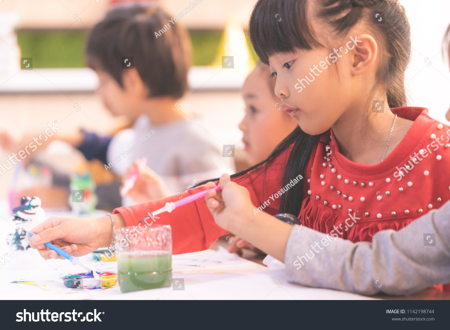 Asian girl is drawing in kindergarten art classroom