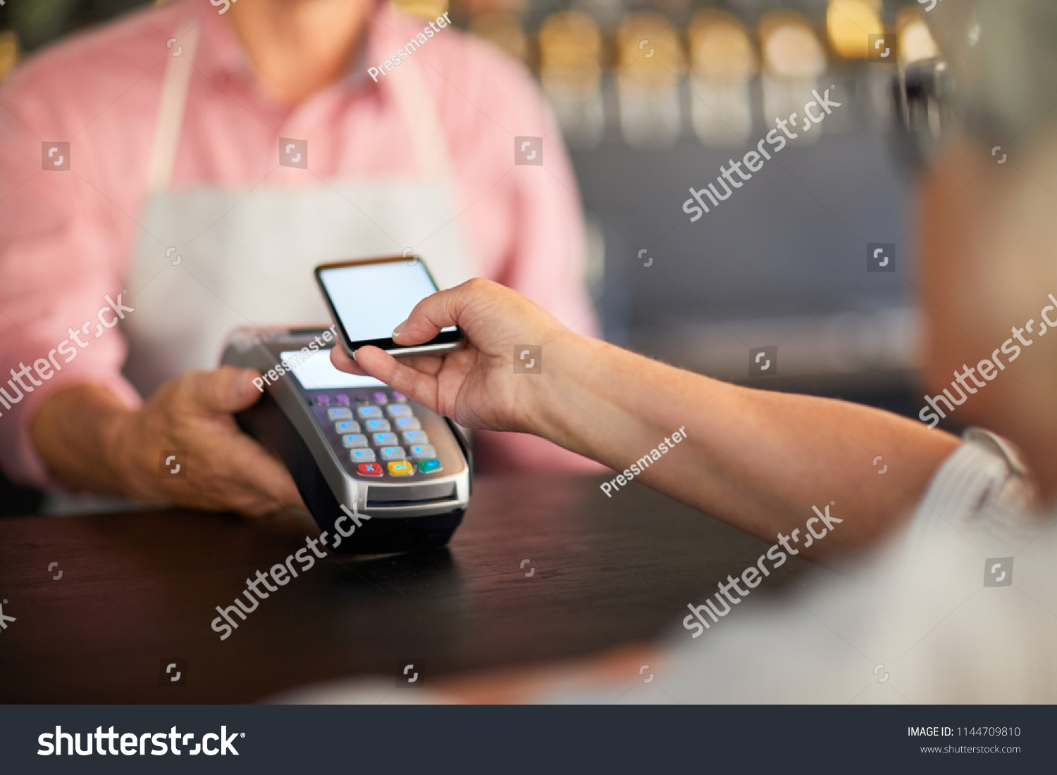 Modern visitor paying through mobile payment system in smartphone after eating in cafe