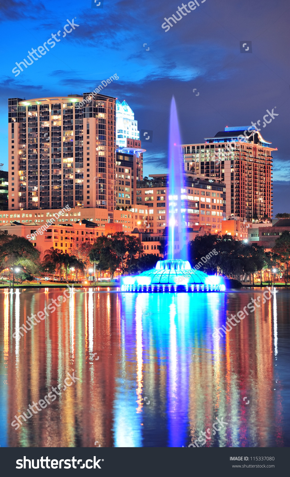 Fountain closeup with Orlando downtown skyline over Lake Eola at dusk with urban skyscrapers and lights.