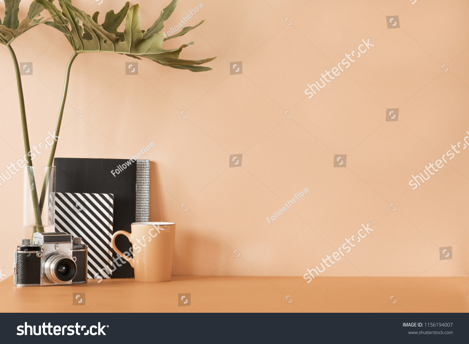 Creative desk with copy space. Empty pastel orange wall. Minimalistic concept of modern interior..