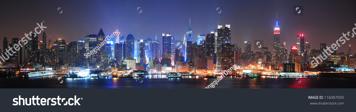 New York City Manhattan midtown skyline at night with skyscrapers lit over Hudson River with reflections.