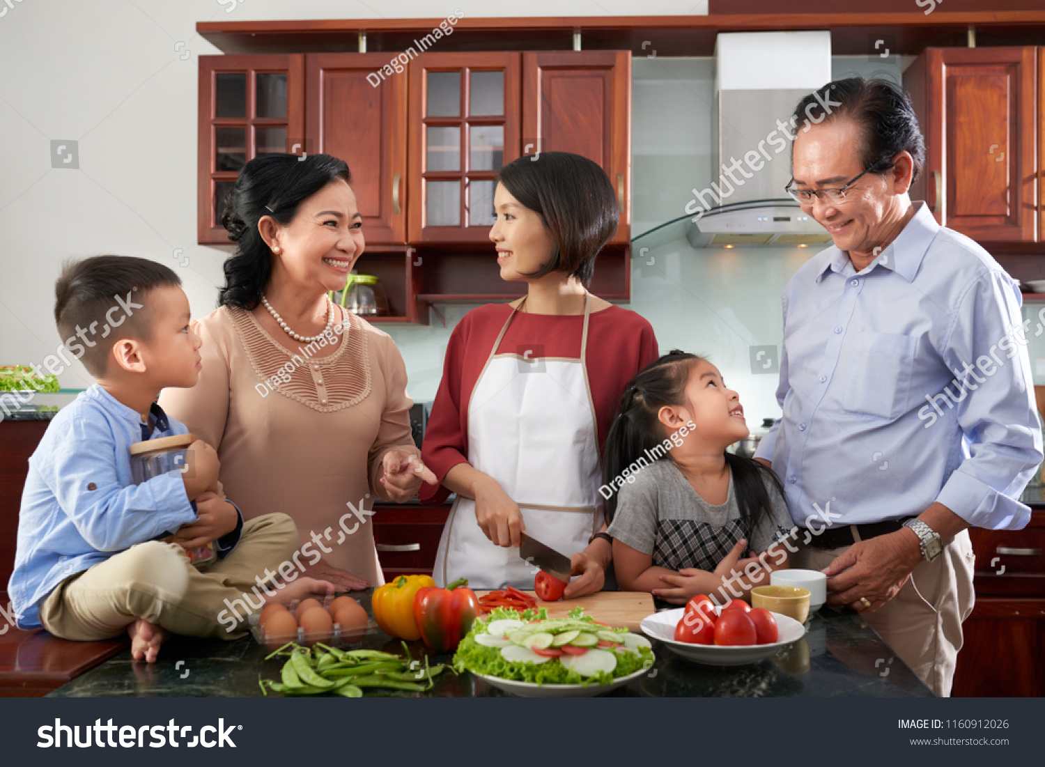Cheerful Vietnamese family gathered in kitchen to cook dinner