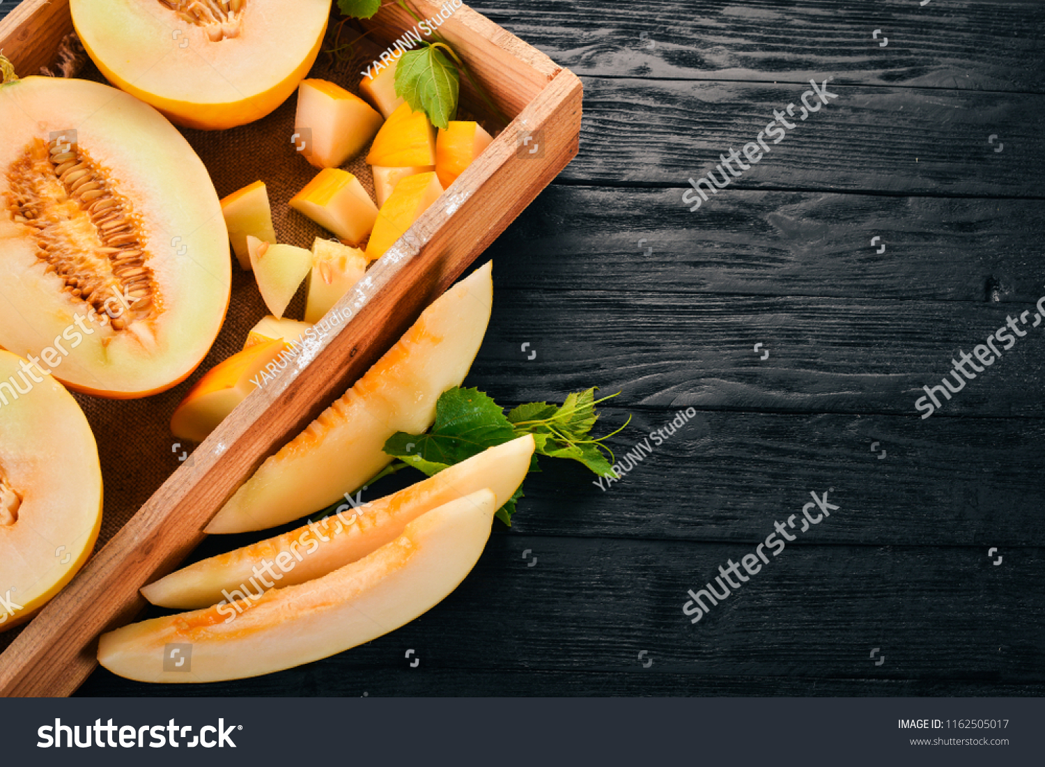 Melon in a wooden box. Sliced to pieces of melon. On a wooden background. Free space for text. Top view.