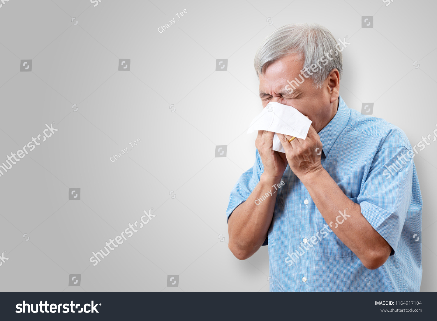 Older asian man is having flu and sneezing from sickness seasonal virus problem with isolated background. Fever and cold in senior people with influenza illness and health insurance concept.