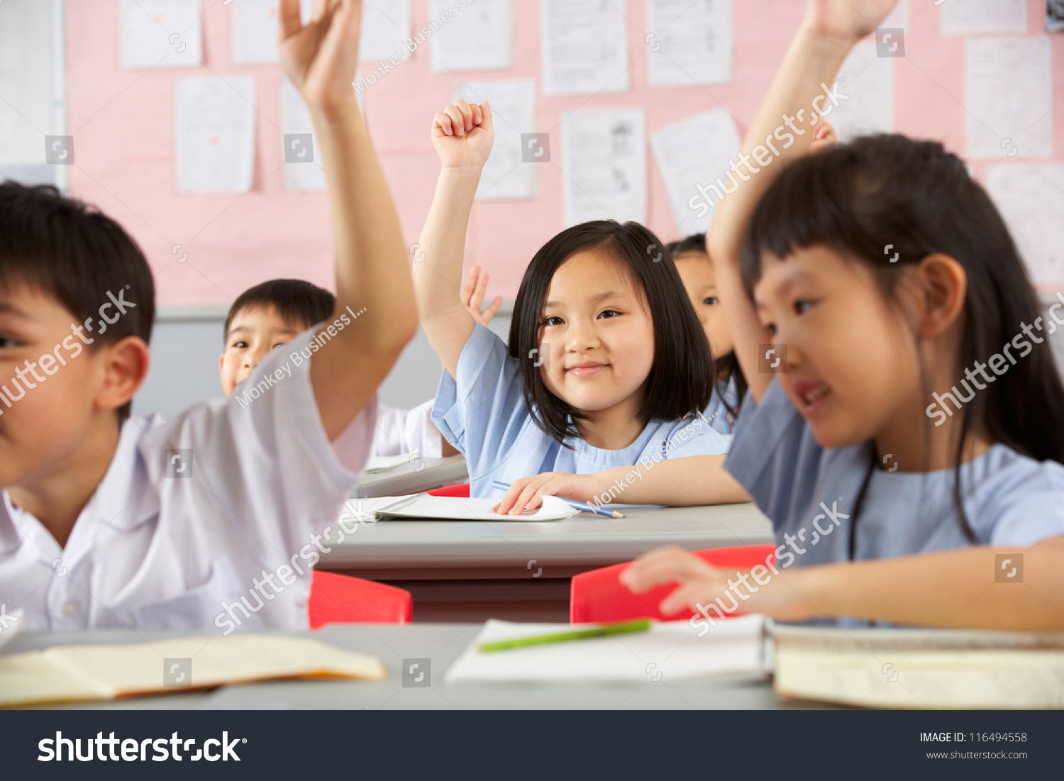 Group Of Students Working At Desks In Chinese School Classroom