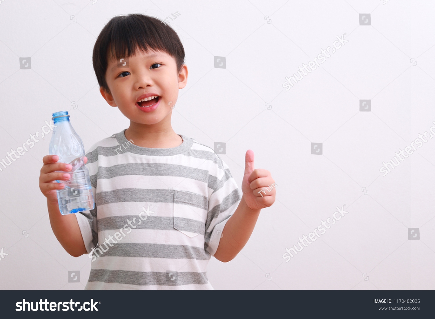 Cute little asian boy showing thumb up sign with a bottle of water isolated on white background