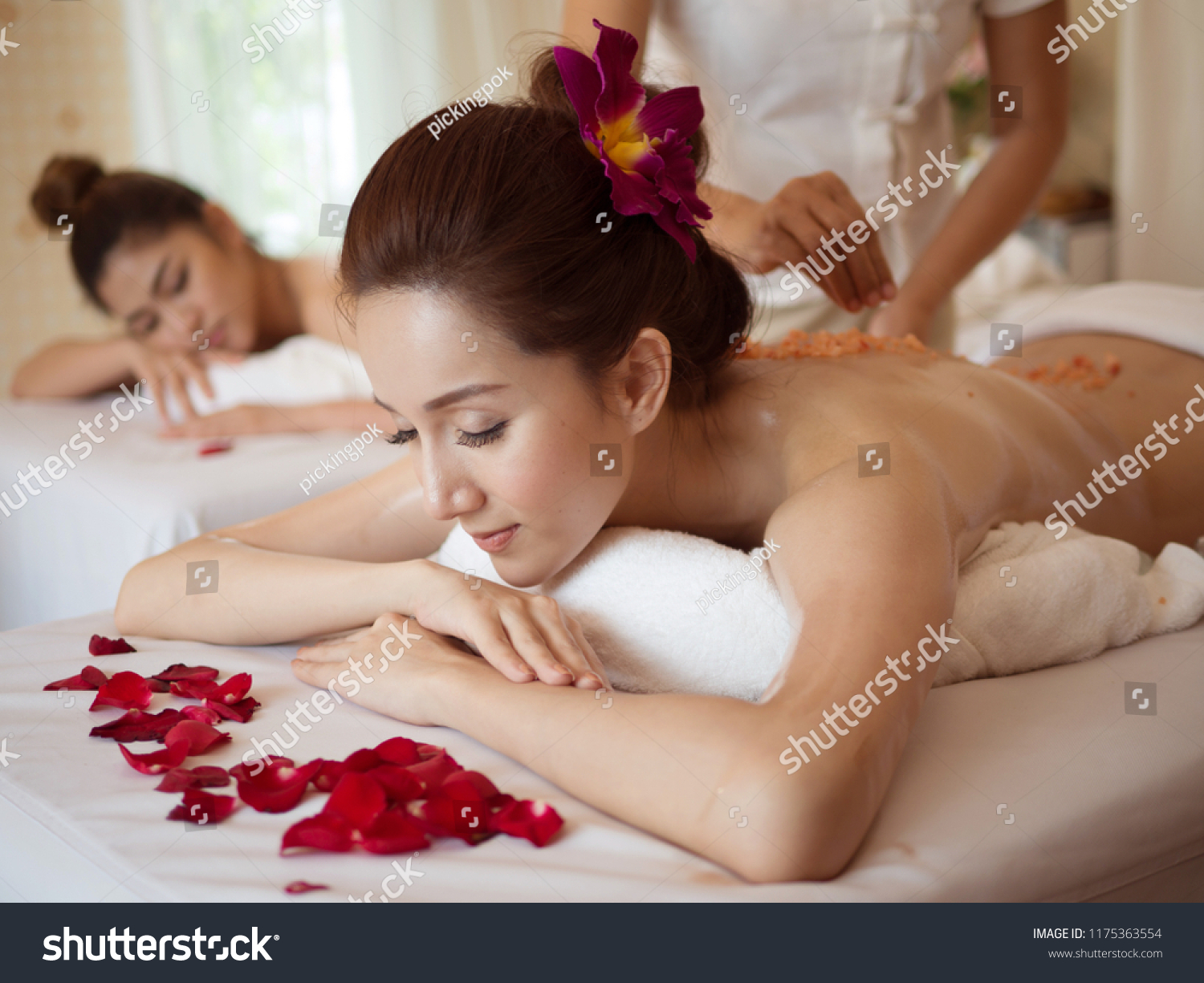 Young Asian woman receiving salt massage in spa salon