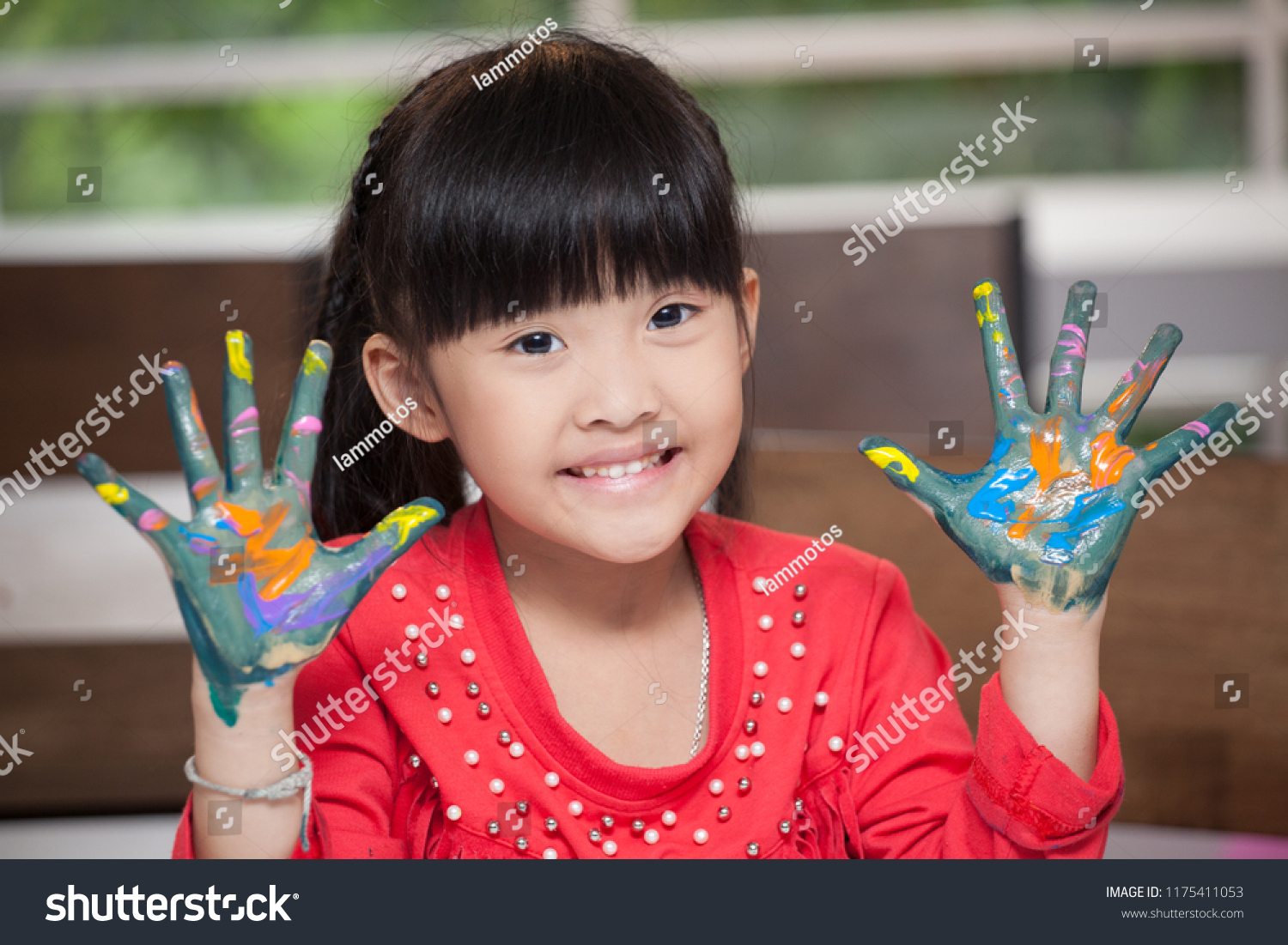 Cute asian little girl with hands in paint   in classroom school  concept - happy children showing painted hand palms at preschool . Early education . kid in kindergarten . intelligence