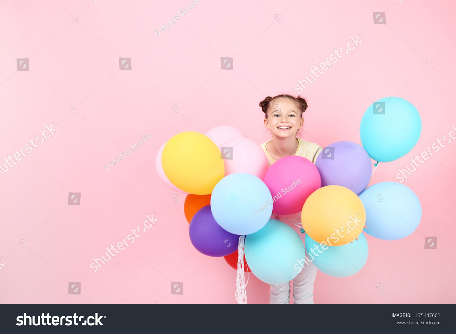 Cute young girl with colored balloons on pink background