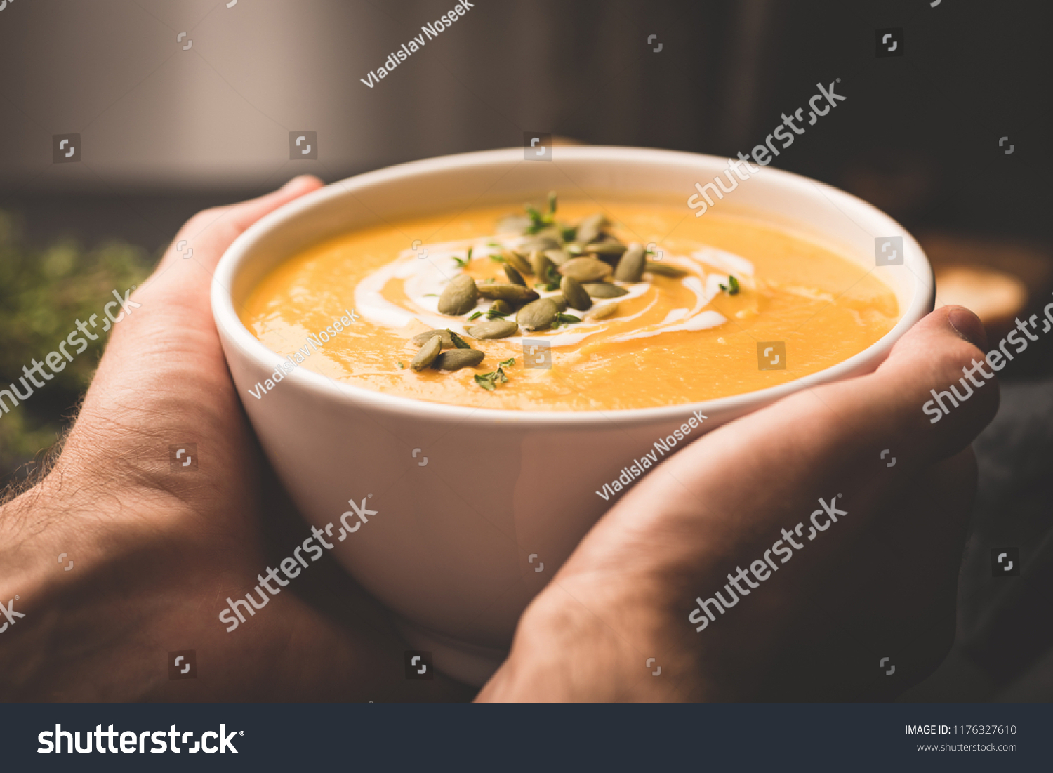 Bowl of warm pumpkin soup in hands. Holding bowl of vegan pumpkin soup. Comfort food. Toned image selective focus