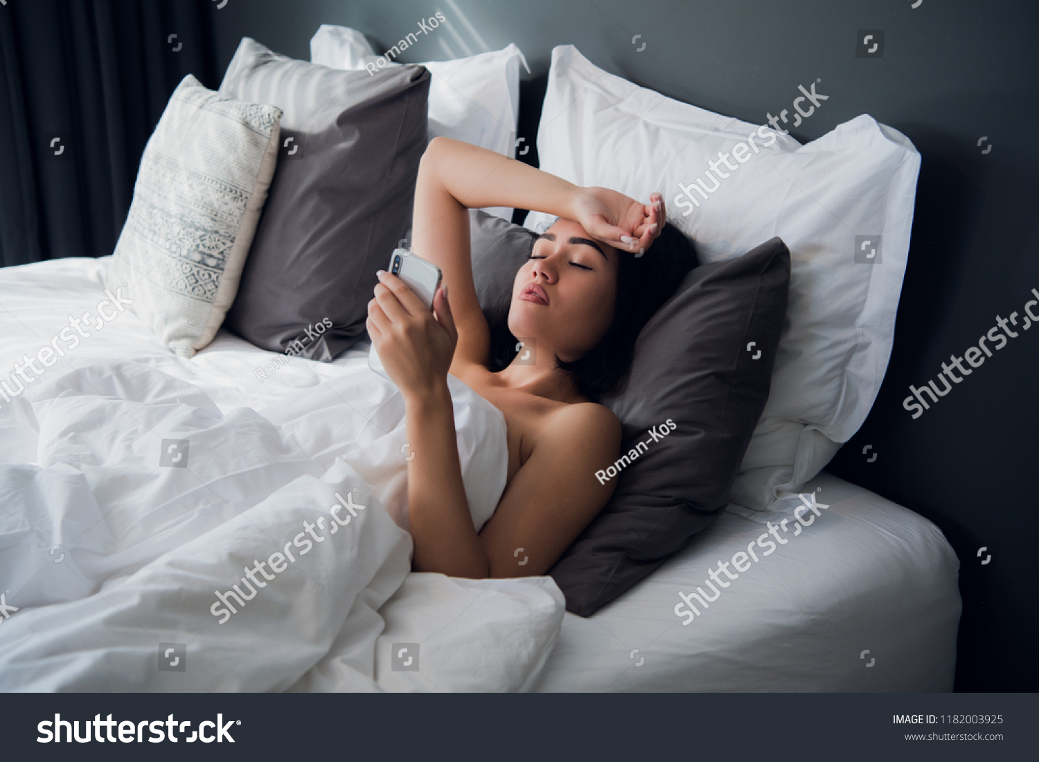 Sick beautiful woman lying in bed with high fever. Cold flu fever and migraine with a thermometer and phone. In stress.