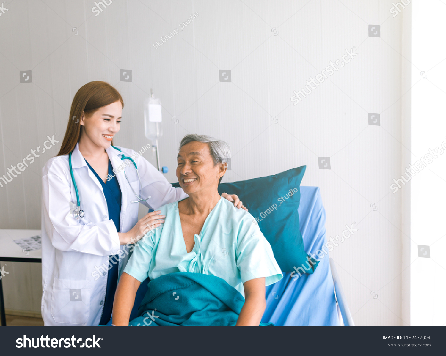 Beautiful Asian doctor taking care of senior patient in hospital bed