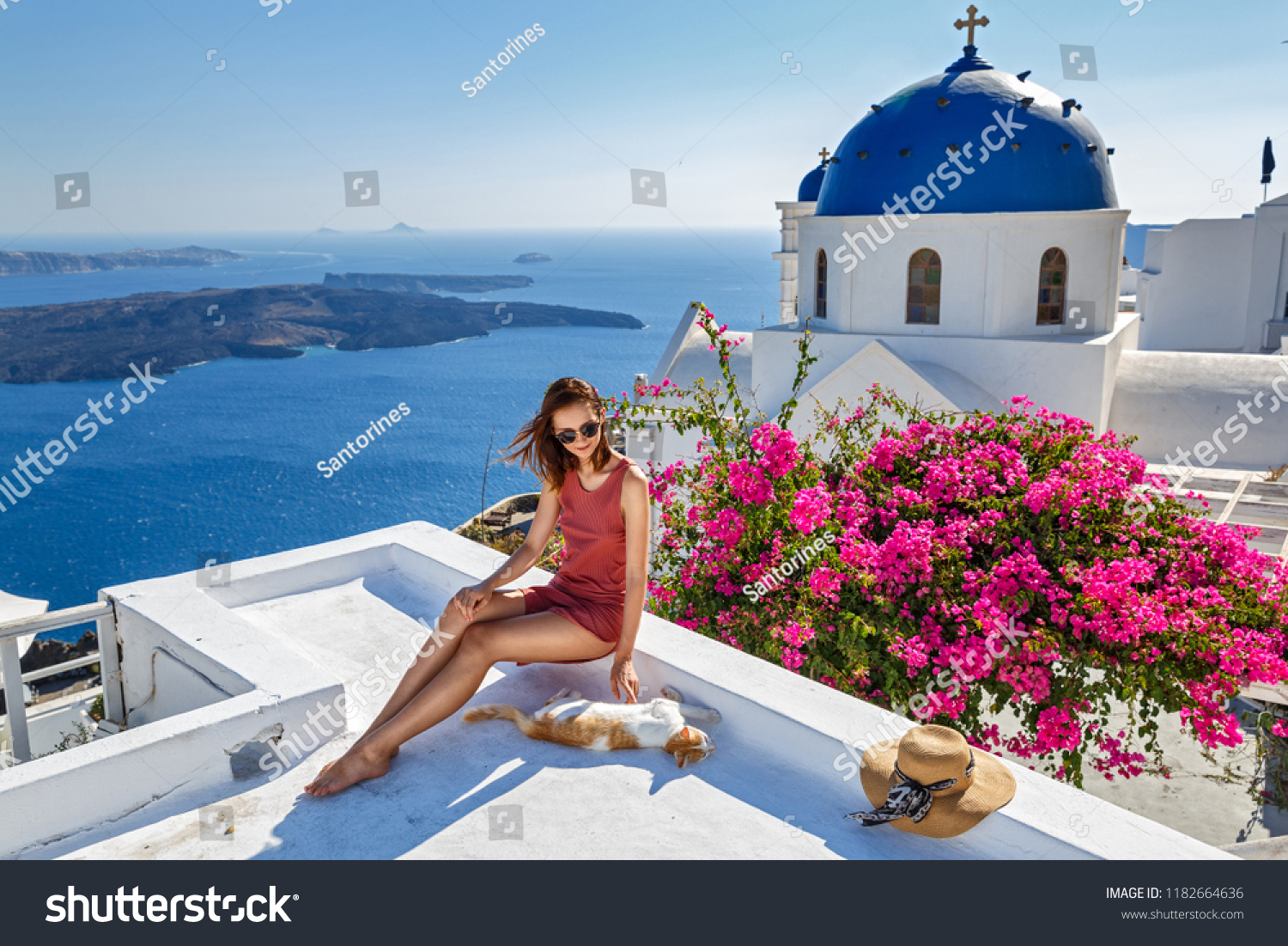 Young woman on Santorini island and red cat