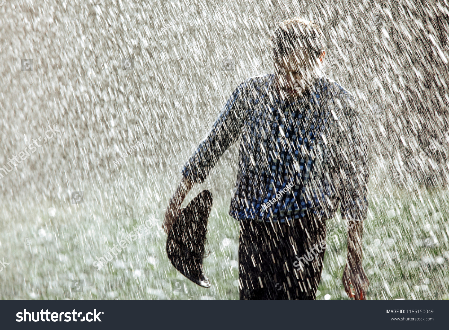 The farmer in the hat is enjoying the rain. Young man getting wet under the rain in summer.