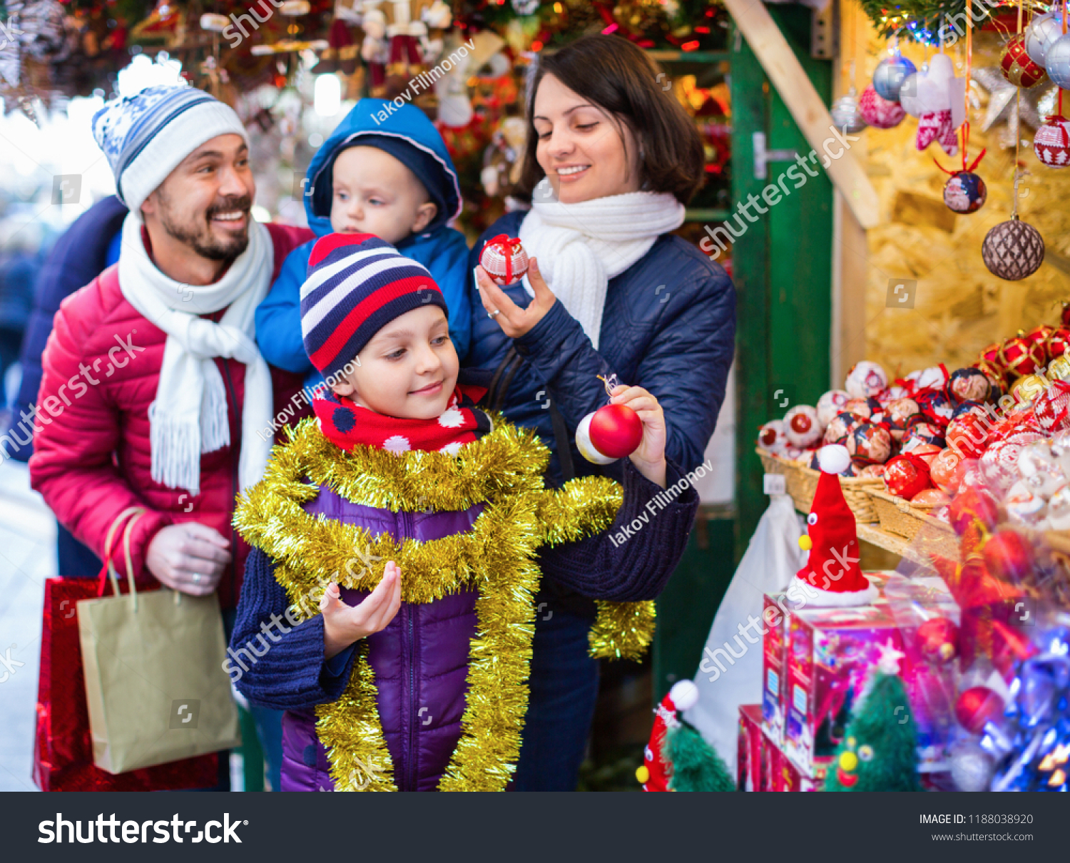 Ordinary cheerful  parents with kids choosing X-mas decorations in market