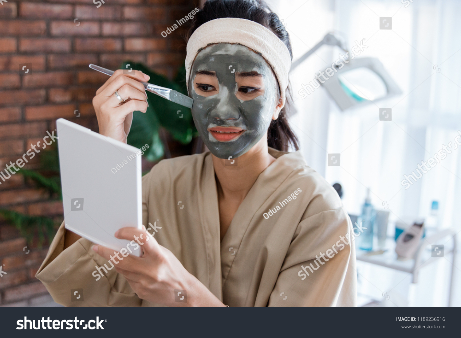 Young woman using facial mask mud herself at home