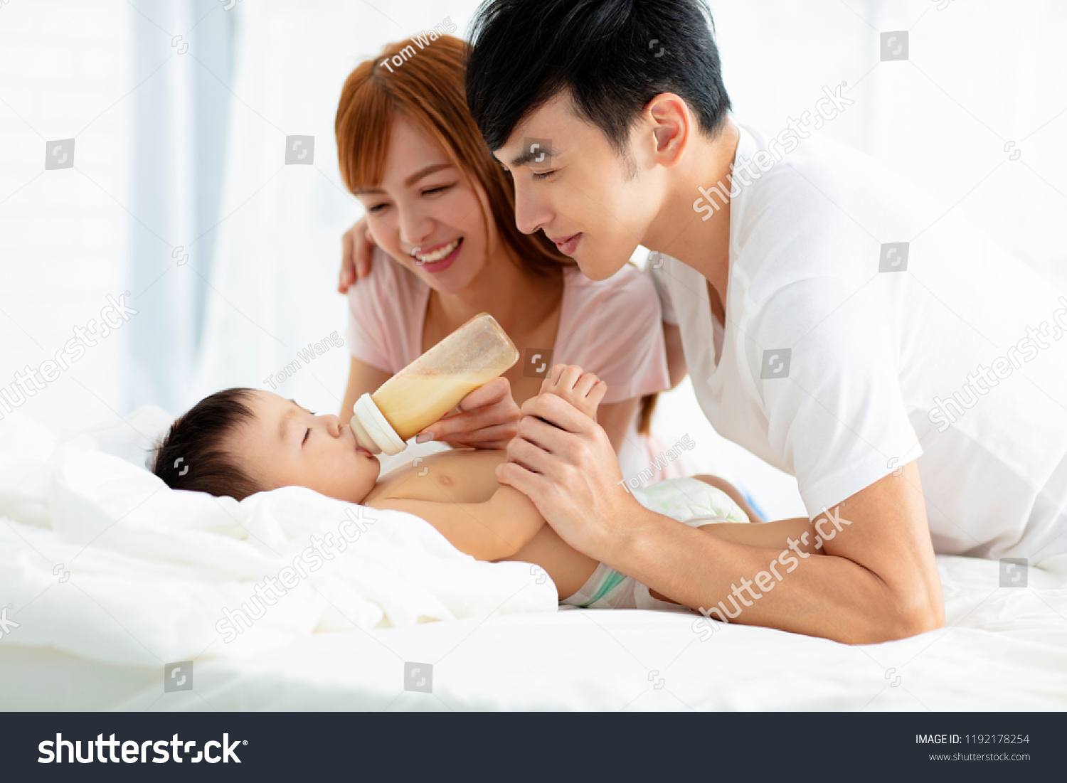 happy father and mother feeding baby from bottle