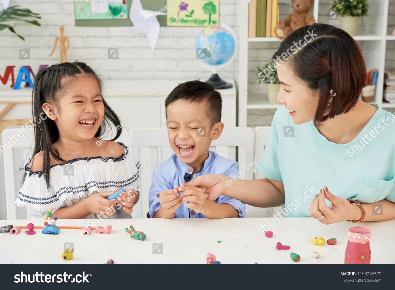 Laughing children and teacher making toys out of playdough