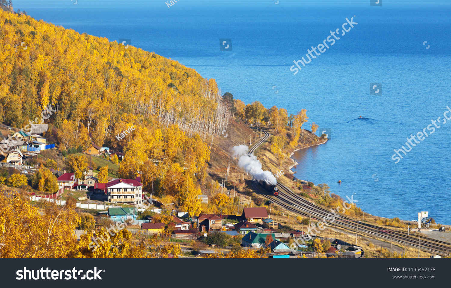 Lake Baikal. View of the Circum-Baikal Railway from above on an autumn day. Tourist excursion historic locomotive arrives in the village of Kultuk. Tourists take pictures of the train
