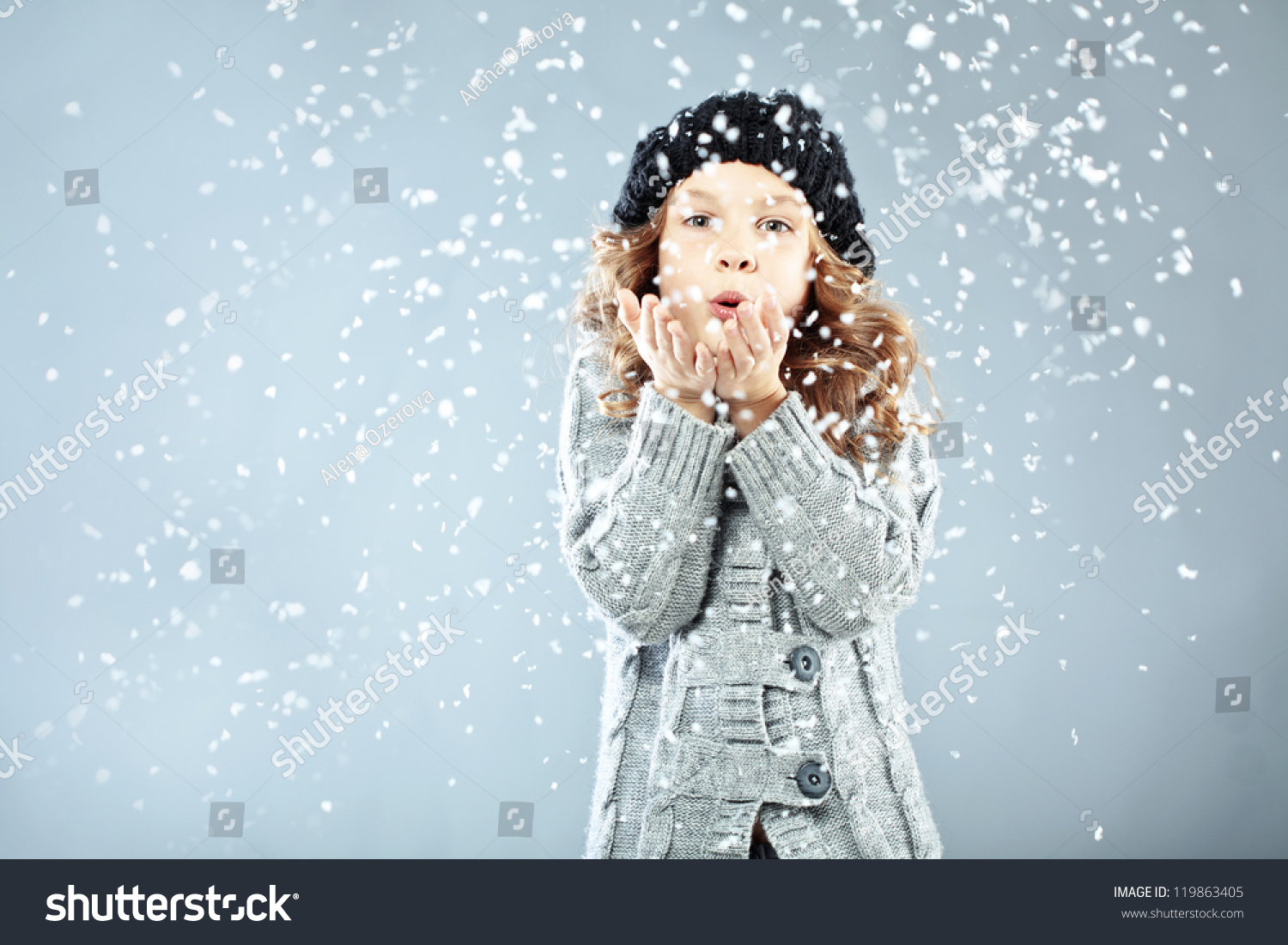 Winter portrait of cute little girl wearing warm cozy clothes studio shot with snow