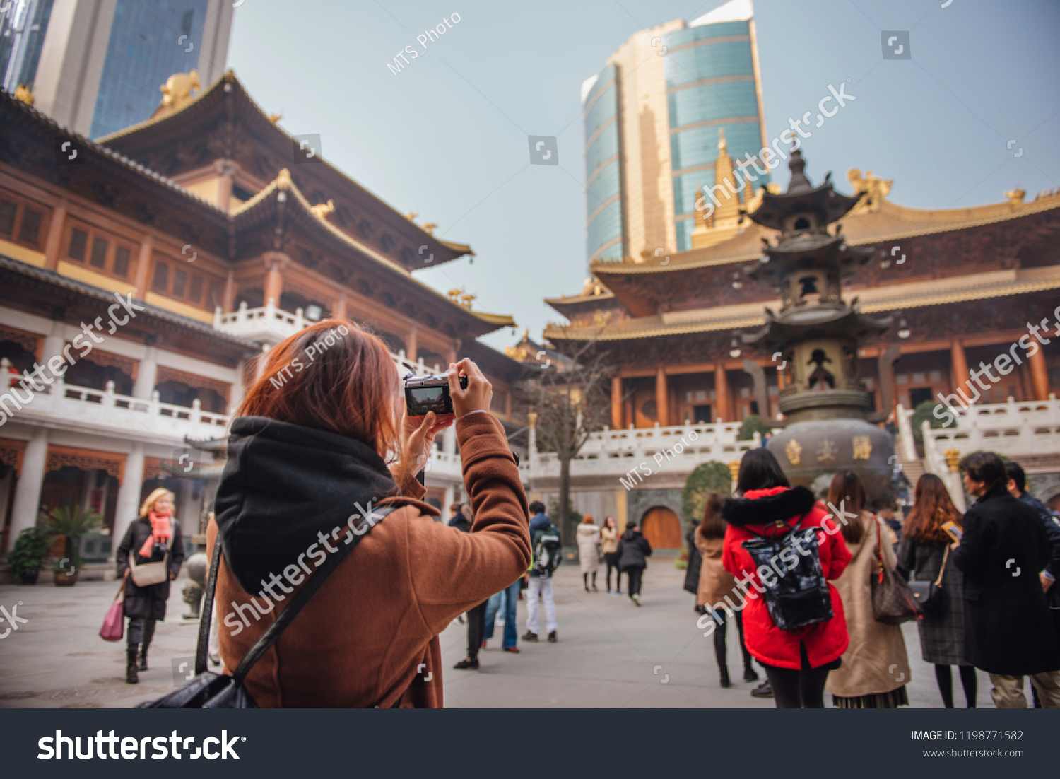 Rear view of young woman traveler taking photo picture at temple in china. Young asian woman in jacket clothes using camera take a picture of temple in shanghai.