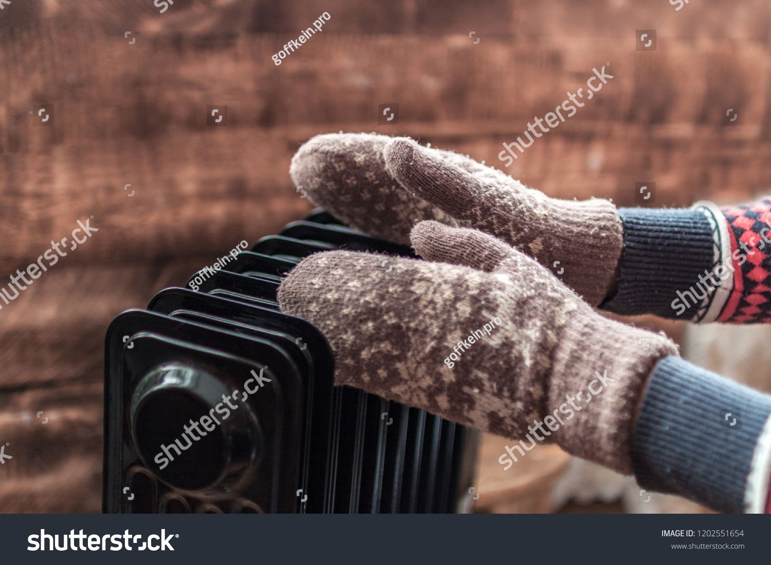 Women's hands in Christmas warm winter mittens on the heater. Keep warm in the winter cold evenings. Heating season