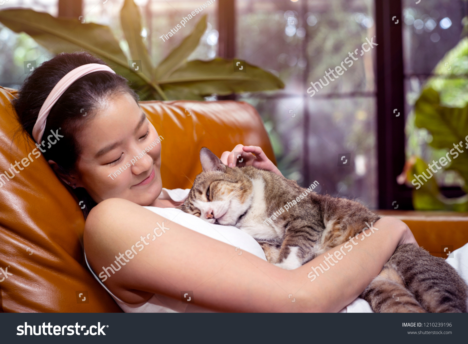 asian woman and tabby cat on sofa