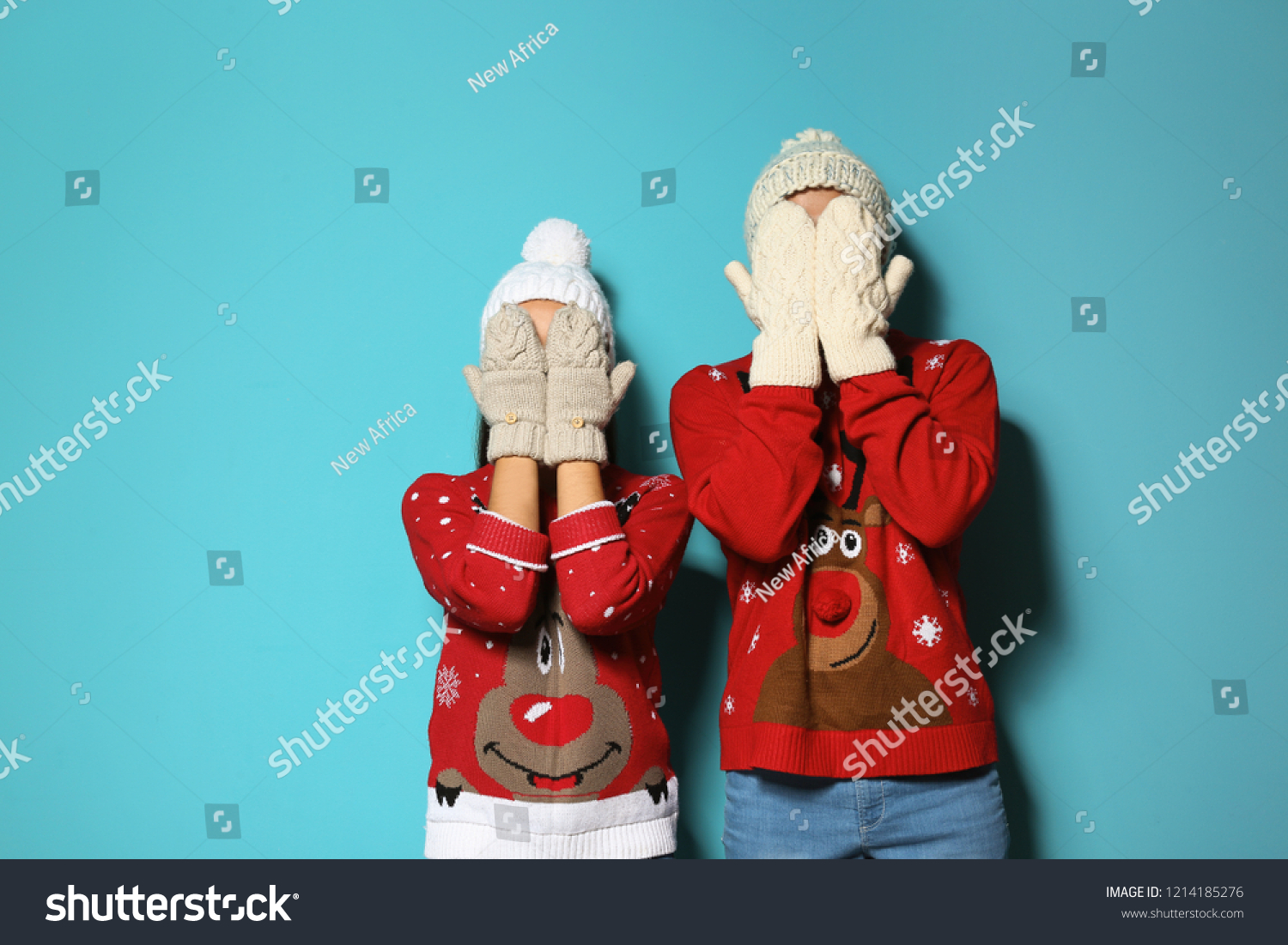 Young couple in Christmas sweaters and knitted hats on color background