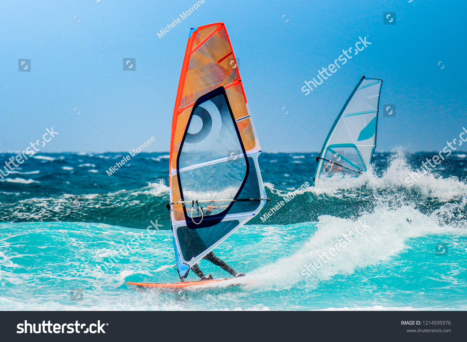 water sports: windsurfers with colored sails in oceanic blue water