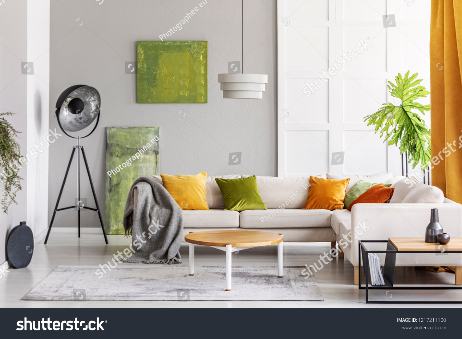 Paintings on the wall and industrial lamp in the corner of elegant living room interior with golden lime accents real photo with copy space