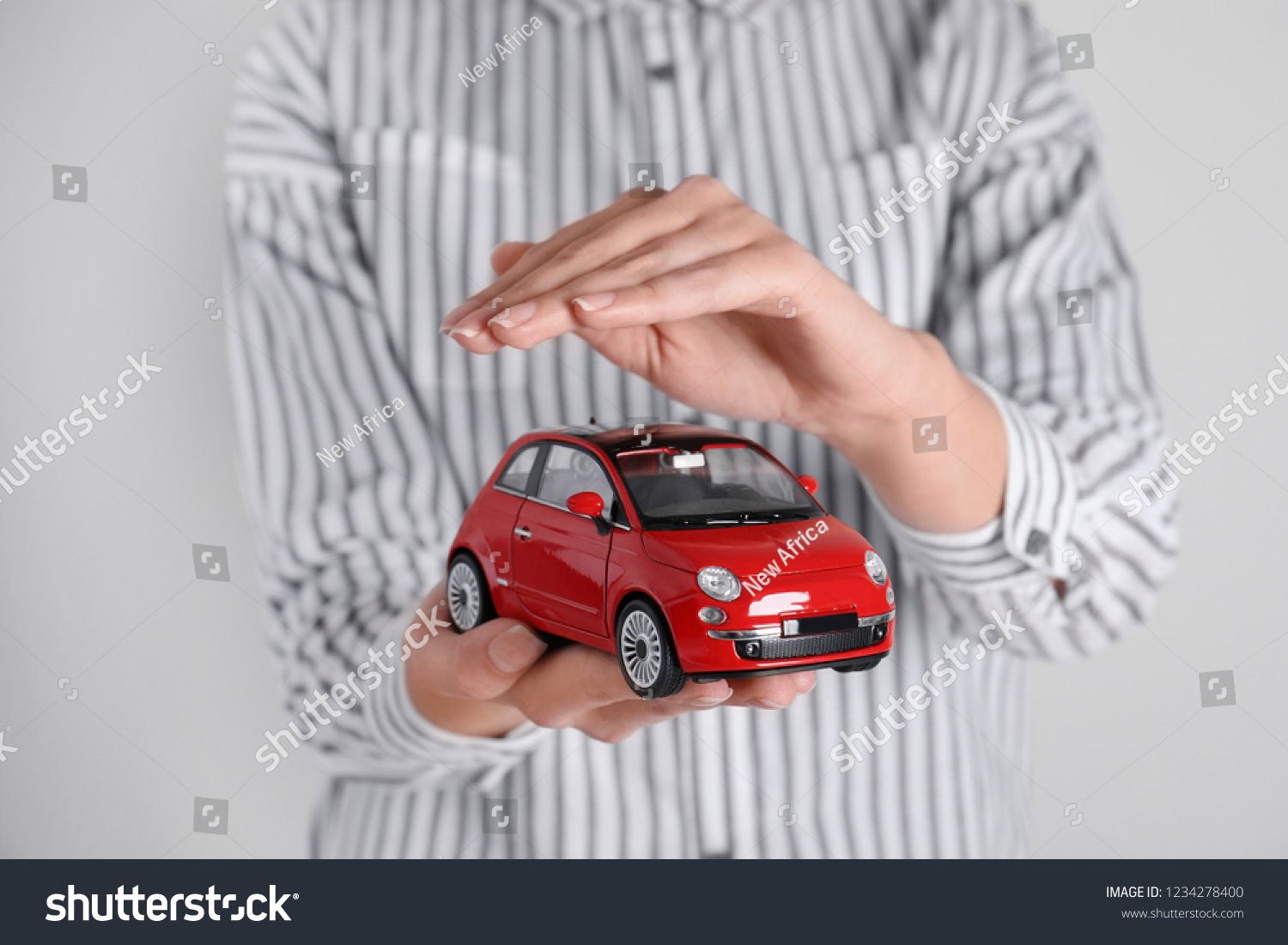 Insurance agent covering toy car on grey background  closeup