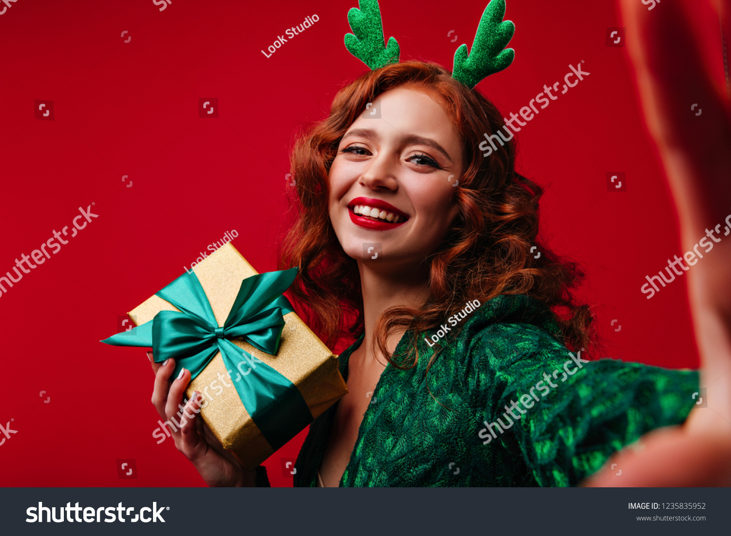 Laughing dreamy woman with ginger hair making selfie in christmas. Jocund white lady with new year gift smiling to camera.