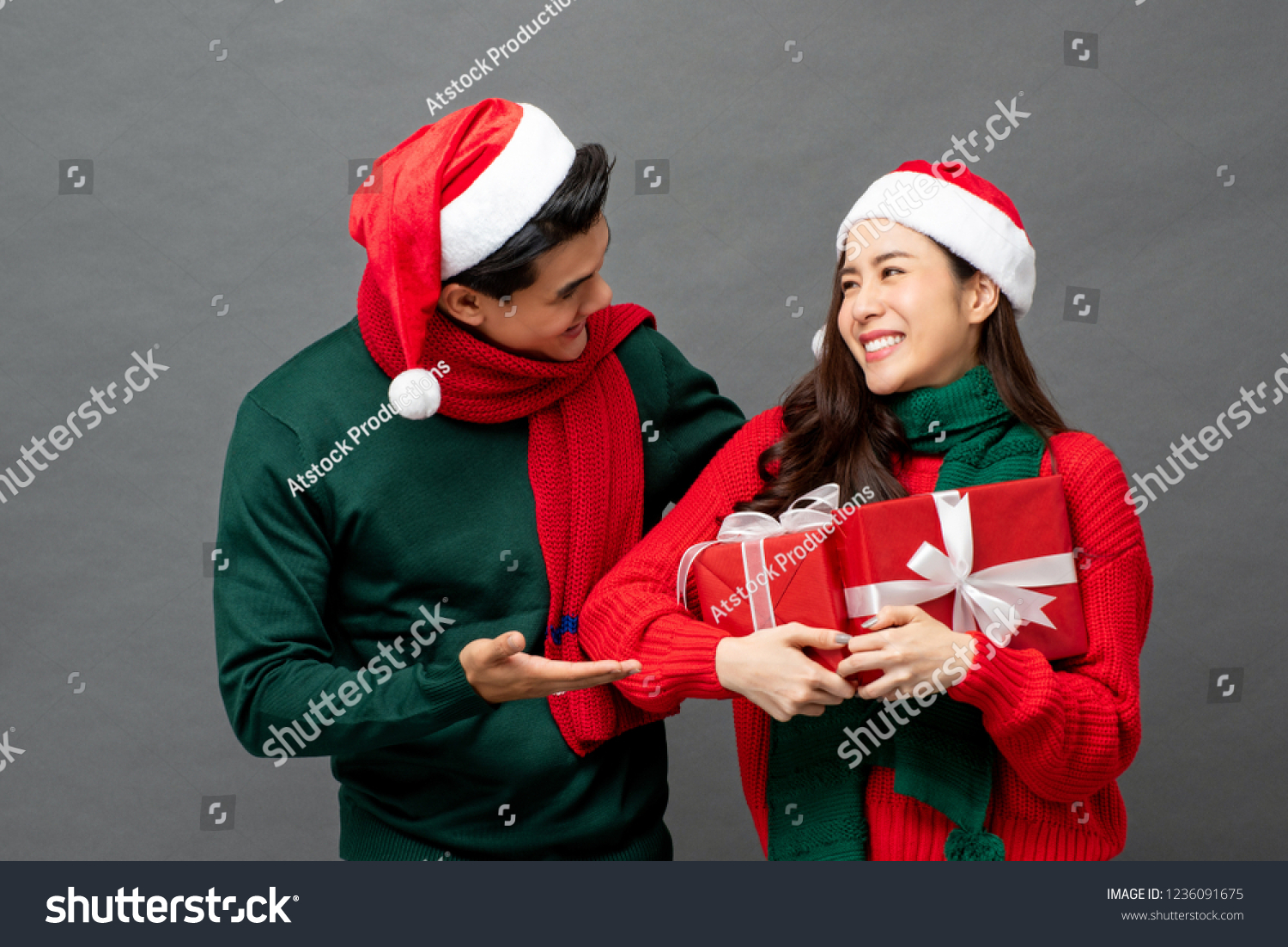 Happy Asian woman being surprised with Christmas gift boxes by her boyfriend