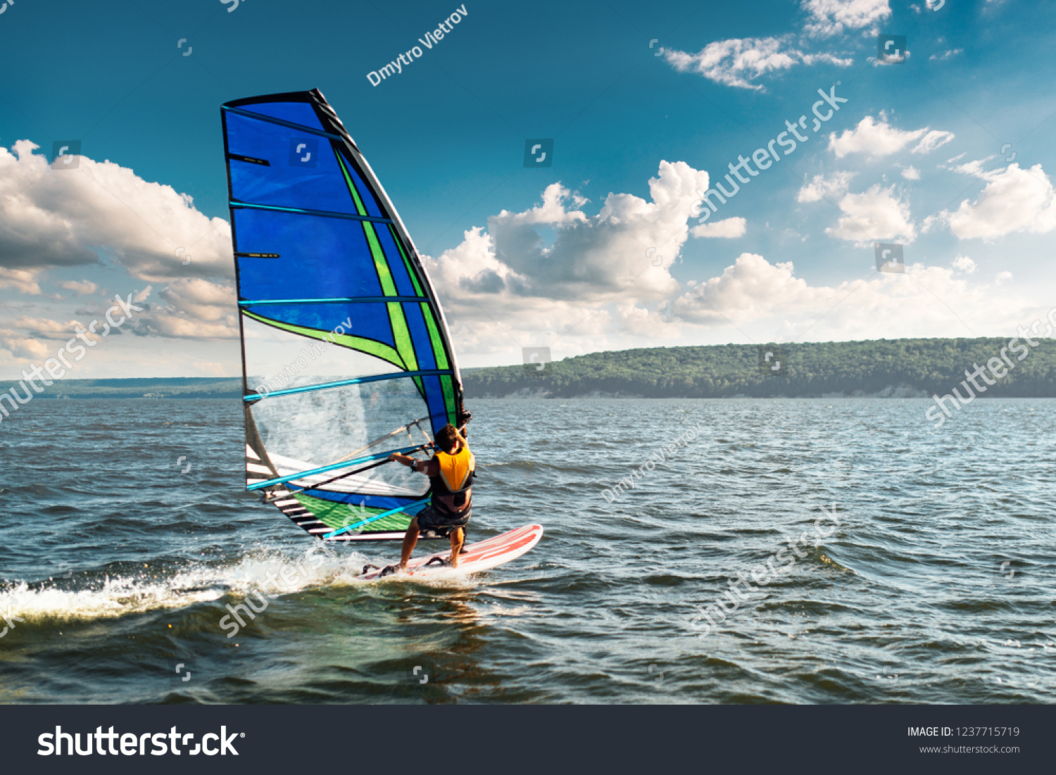 the man athlete rides the windsurf over the waves on the lake