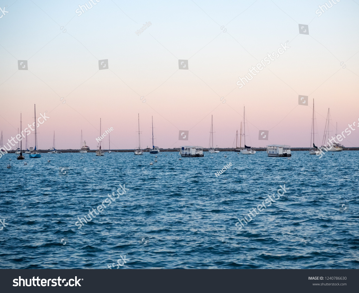 Sail boats in Michigan lake in Chicago at dusk.