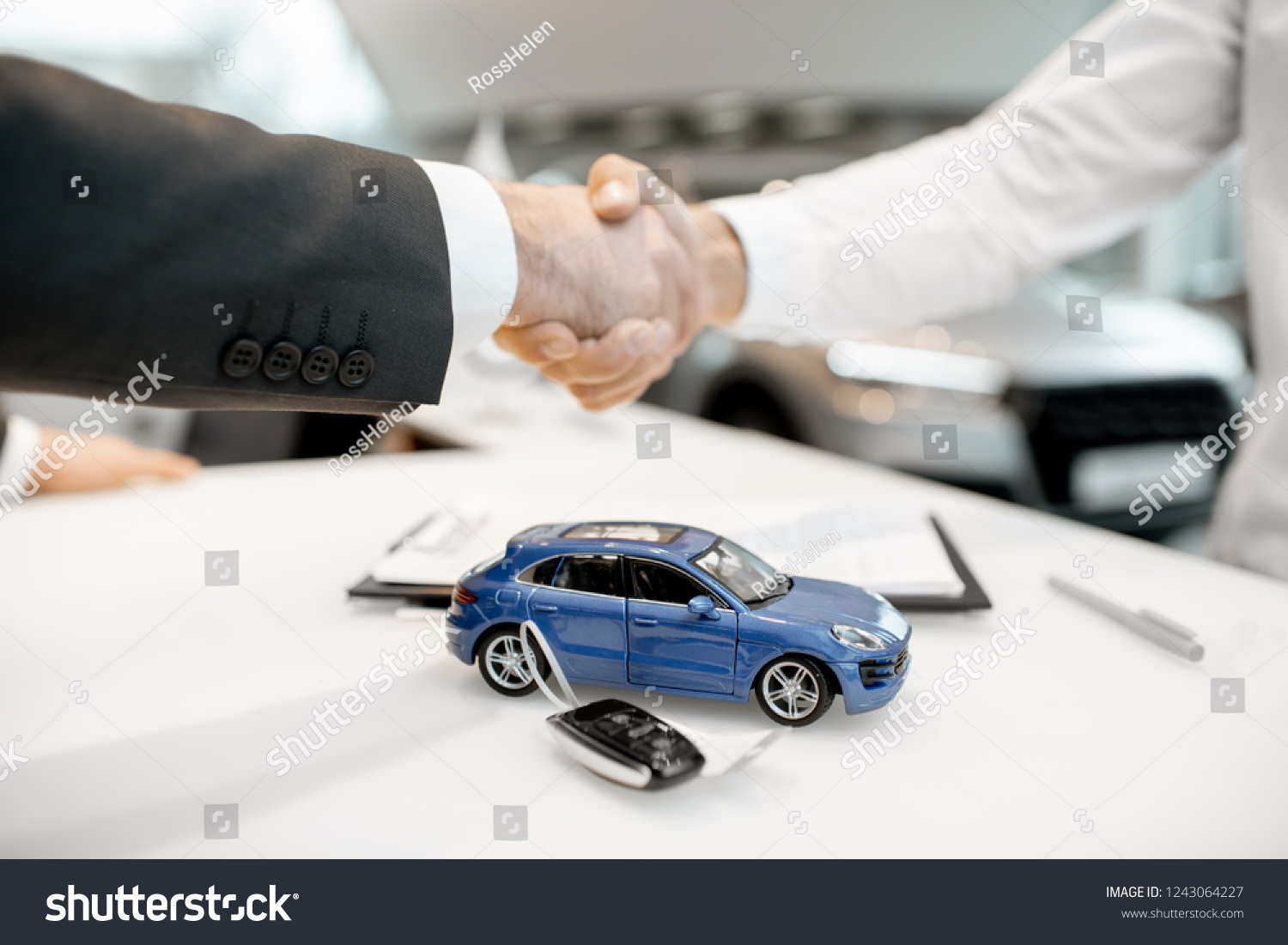 Close-up of a handshake at the table with toy car and keys. Car buying concept