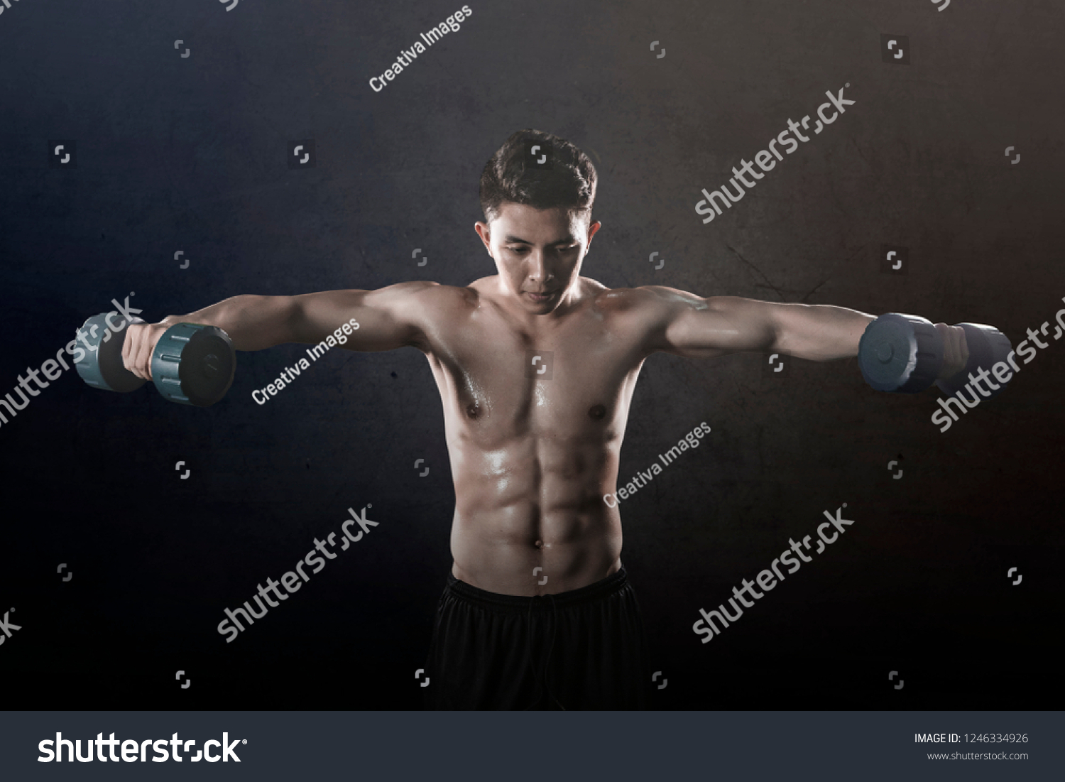 Young Asian man looks sweaty while doing exercises with two dumbbells 
