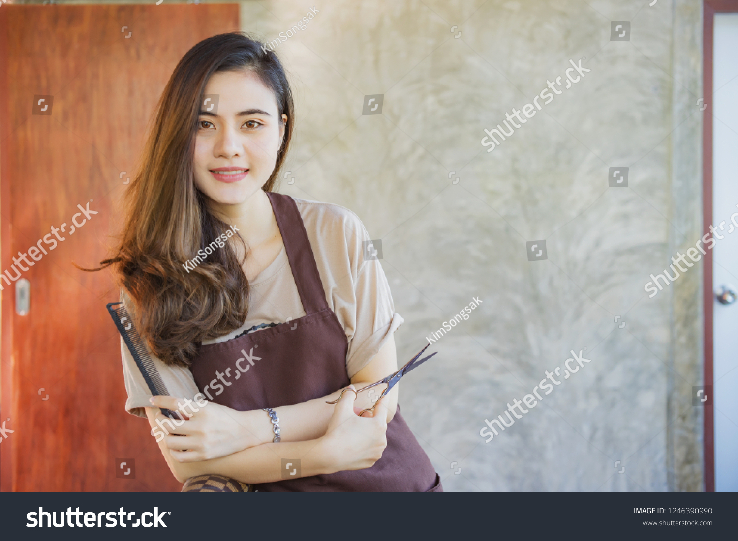 Professional woman hairdresser in salon with scissors in hand.