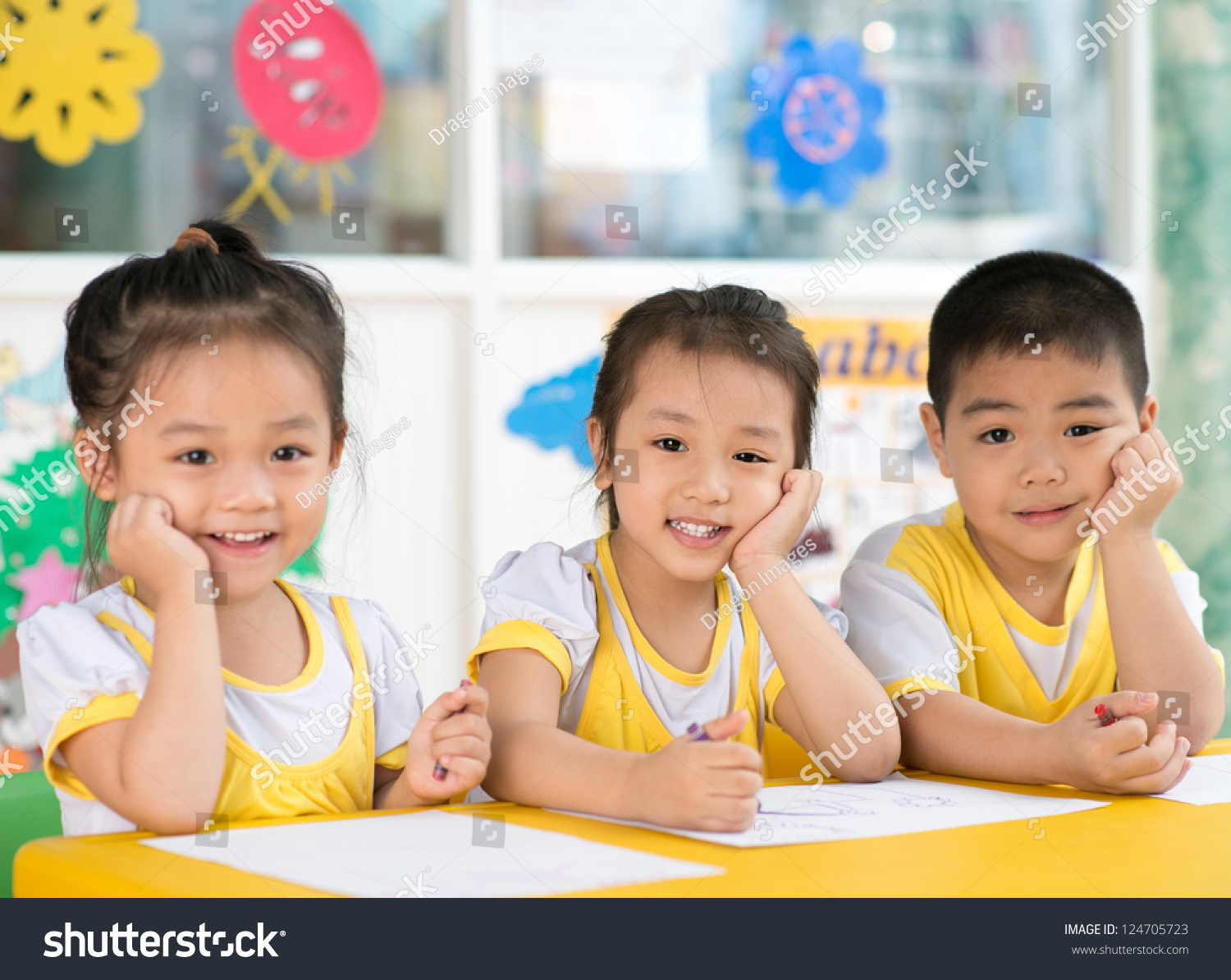 Asian children sitting behind the desk in the room
