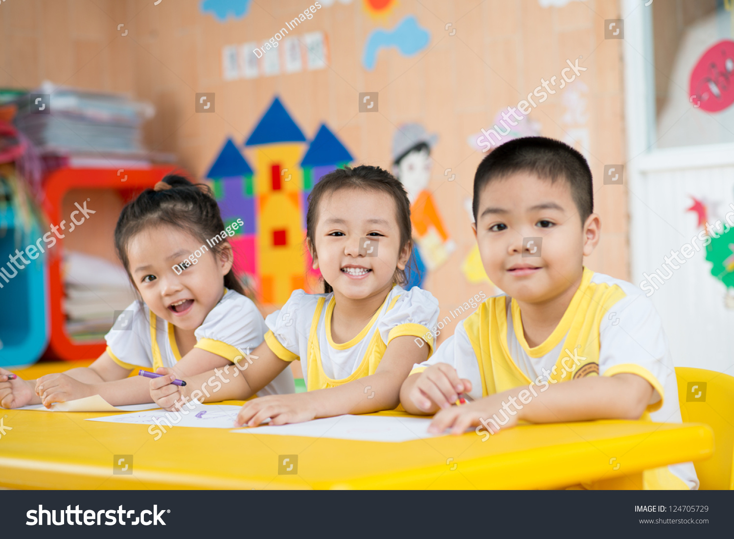 Three children sitting behind the desk and smiling